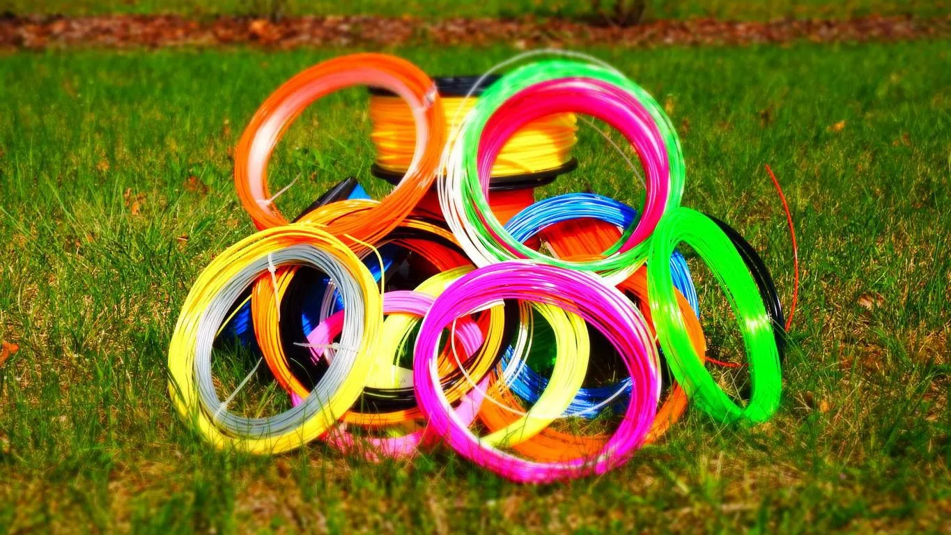 Bunte Rollen 3D-Druck-Filament in Neonfarben auf einer Wiese