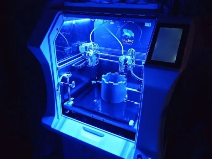 Leapfrog-3D-Drucker mit blauer Innenbeleuchtung und einem gedruckten Bauteil auf der Druckplatte
